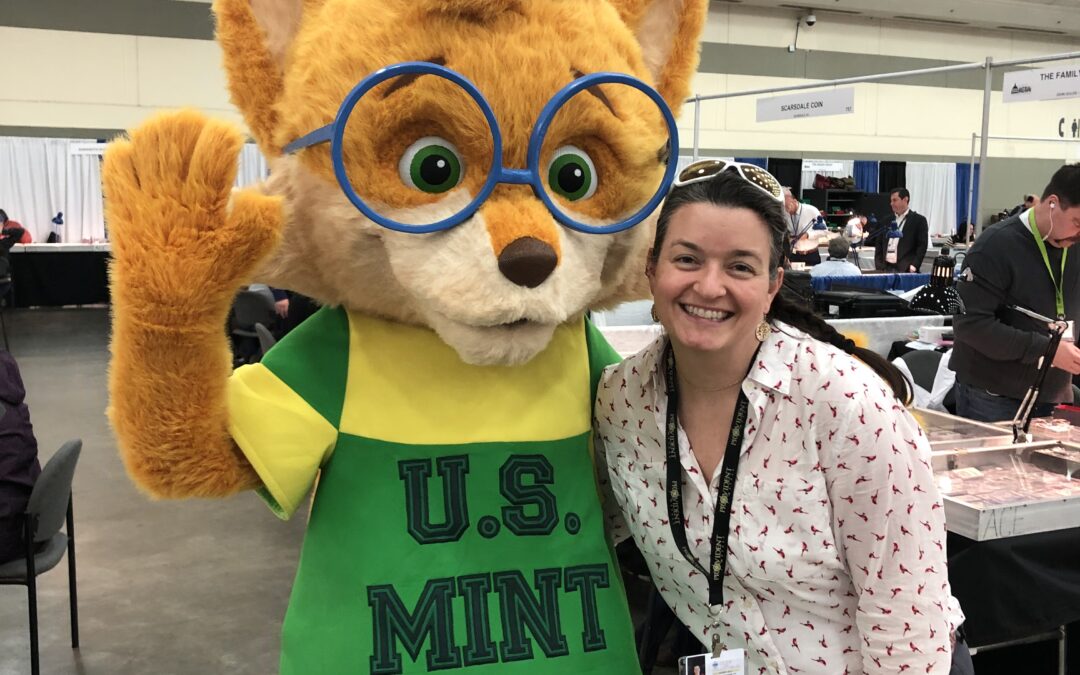 Ailie wth US Mint mascot at the Whitman Expo (Young lady next to fox charactger)